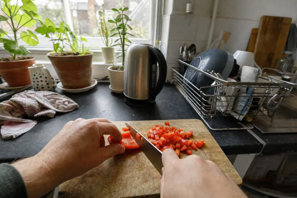 First-person view of two hands dicing a red pepper in a home kitchen